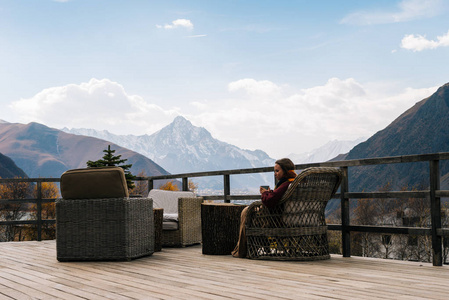 一个年轻的女孩旅行, 坐在阳台上, 欣赏群山的美景。