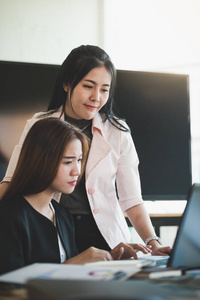年轻的亚洲业务工人与便携式计算机在办公室工作。业务启动团队精神和集体观念