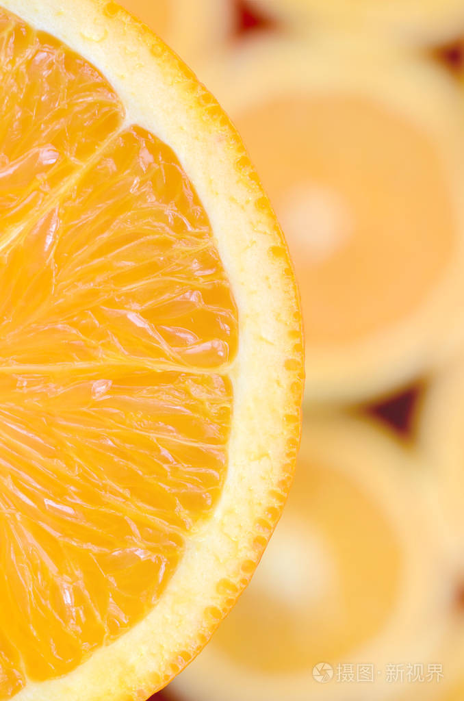 在许多模糊的橙色切片的背景上, 橙色水果片的一个片断的顶部视图.
