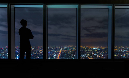 男人看着窗外高高的城市上方的大窗户照片
