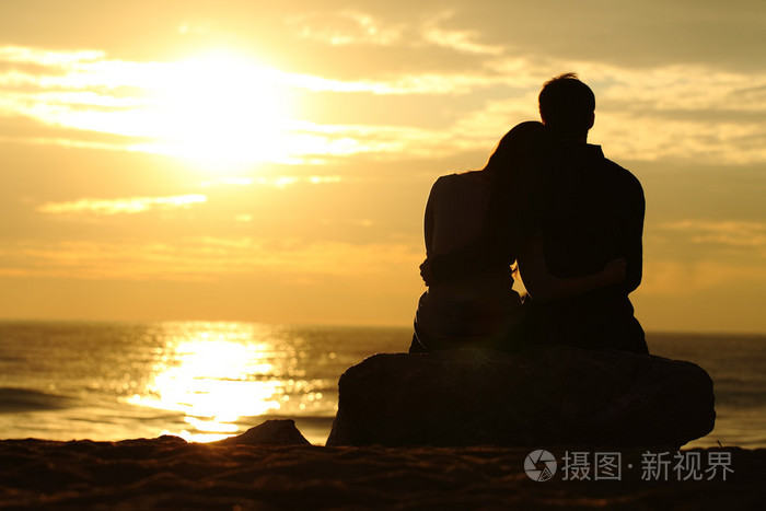 在沙滩上看日落的夫妇剪影