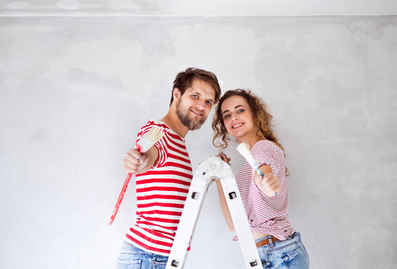 对年轻情侣在他们的新房子的绘画墙