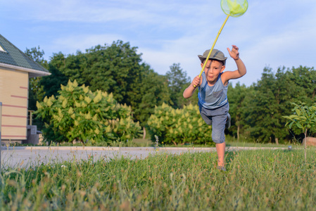 可爱有趣的小男孩跑去捉蝴蝶照片