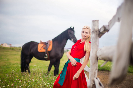 美丽的年轻女子，穿着红色与室外一匹马