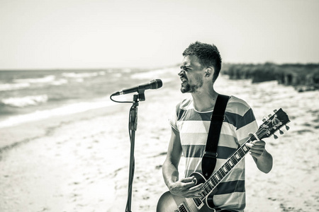 在海滩上，这位音乐家的岩石会弹吉他，唱着麦克风，休闲和创造力的概念