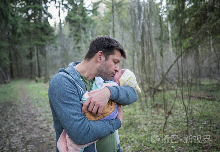 父亲抱着儿子刚出生的婴儿的手亲吻他的温柔