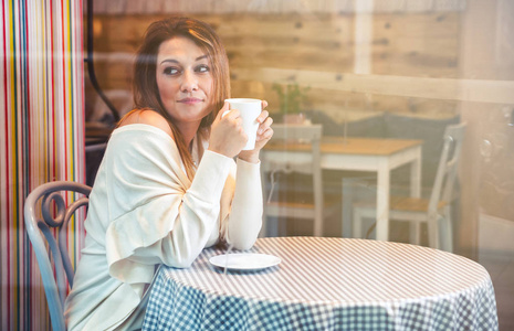 孤独的女人,看的东西在咖啡馆里喝咖啡时照片