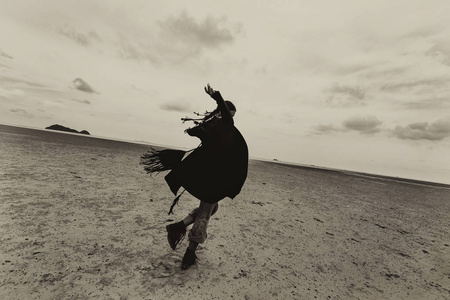 美丽的年轻女子在沙滩上暴风雨天气在旋转照片