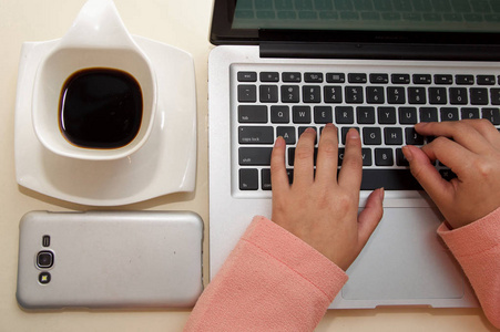 工作办公室 笔记本电脑 杯咖啡和 smarphone 在图片中的女商人手的特写。经营理念