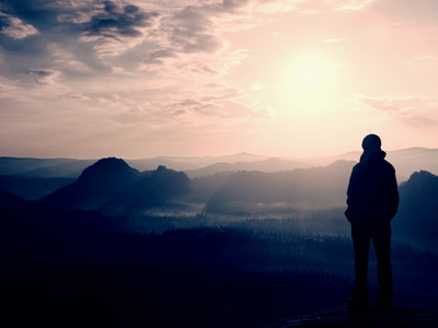 徒步旅行者站在砂岩岩岩帝国公园和注视着朦胧有雾的早晨谷到太阳的尖角