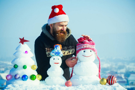 快乐的圣诞老人人把帽子放在雪人