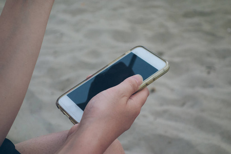 女人在海滩上举行智能手机