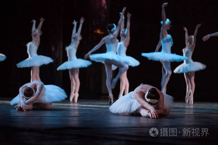 在剧院的舞台上组芭蕾舞女舞者在白色的短裙和紧身衣,其中两个掉了