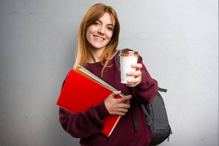 学生女子捧着一杯咖啡在灰色的背景上