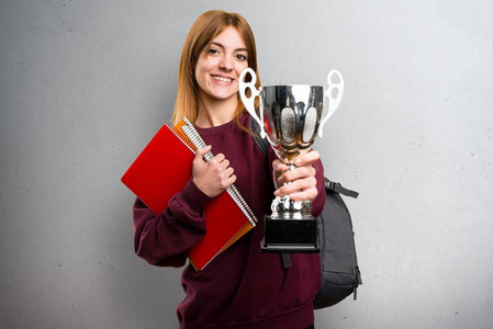 学生女子手拿奖杯在灰色的背景上照片
