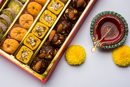 印度甜或 mithai 和油的灯或 diya 礼品盒和鲜花装饰或色彩缤纷的背景下，选择性焦点股票照片