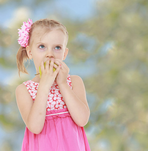 穿着粉红色的连衣裙的小女孩咬苹果，淡绿色背景
