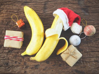 香蕉在圣诞节帽子与装饰在木背景