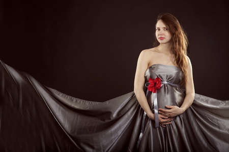 孕妇在一朵红色的花灰色连衣裙