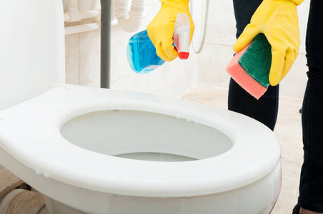 用橡胶手套的女人清洗马桶照片