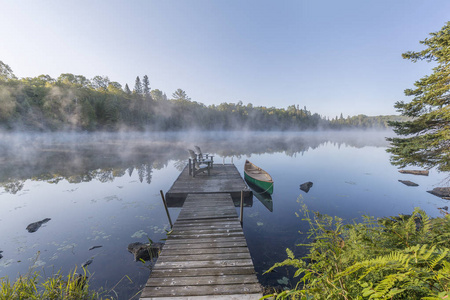 绿色的独木舟和停靠在有雾的早晨安大略省，加拿大