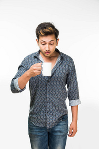 年轻英俊的印度男人喝一杯咖啡，站在白色背景孤立的肖像