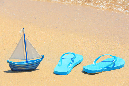人字拖鞋和玩具船在沙滩上
