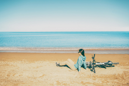 女人和自行车一起在海滩上休息