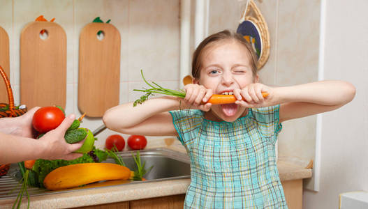 儿童女孩吃胡萝卜 蔬菜和新鲜水果在厨房内，健康食品的概念