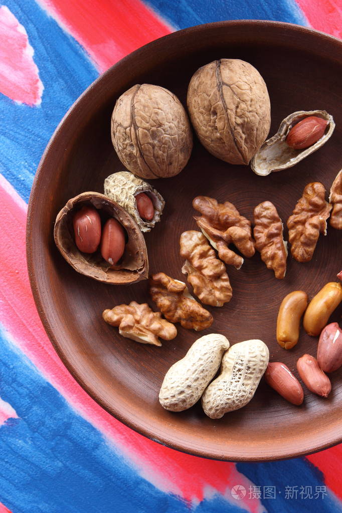 核桃和花生在波普艺术背景上的褐色粘土板上