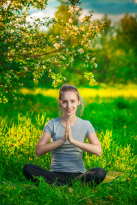 做瑜伽户外在绿色草地上的美丽女人