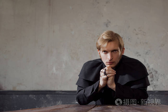 画像的英俊年轻的天主教神父向上帝祈祷.黑暗的风格,概念怀疑