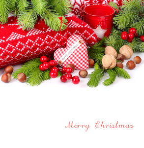 纺织格仔心 坚果和红色浆果接近针织的枕头和分支的白色背景上的一棵圣诞树。圣诞节背景以及放置文本的位置