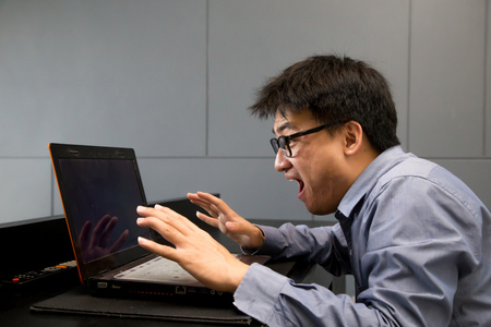 亚洲人用笔记本电脑看着屏幕兴奋惊讶