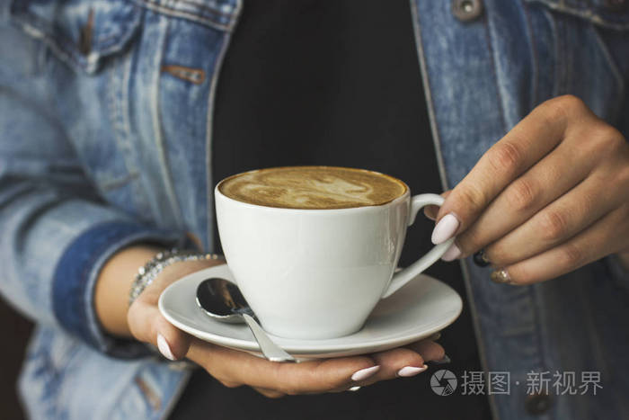 牛仔裤夹克拿着杯咖啡在她手中的少女照片-正版商用图片0cohft-摄图新