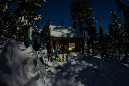 在冬季森林与房子小木屋的滑雪和滑雪板雪在山