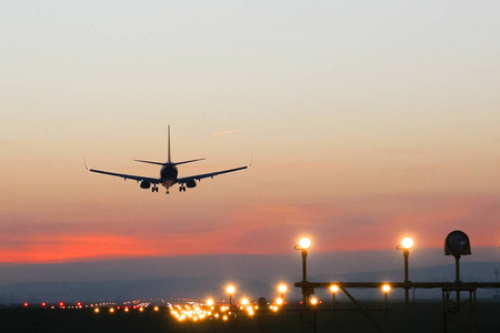 当飞机降落在机场上的日落背景