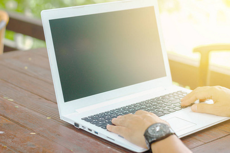 起一个坐在木桌上的笔记本电脑上工作的人的低角度观附近的股票照片