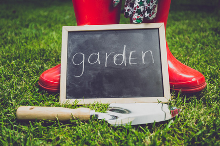 黑板上用词花园躺在花园工具旁边的草地上