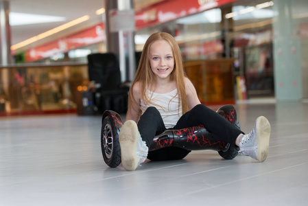 在贸易商城迷你赛格威的快乐和微笑女孩。少年骑上悬停板或 gyroscooter