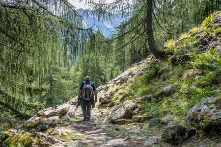 沿着地平线徒步旅行者沿着一条小路走山路照片