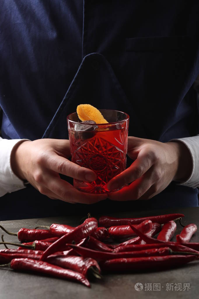 negroni鸡尾酒中的手和红辣椒在桌子上