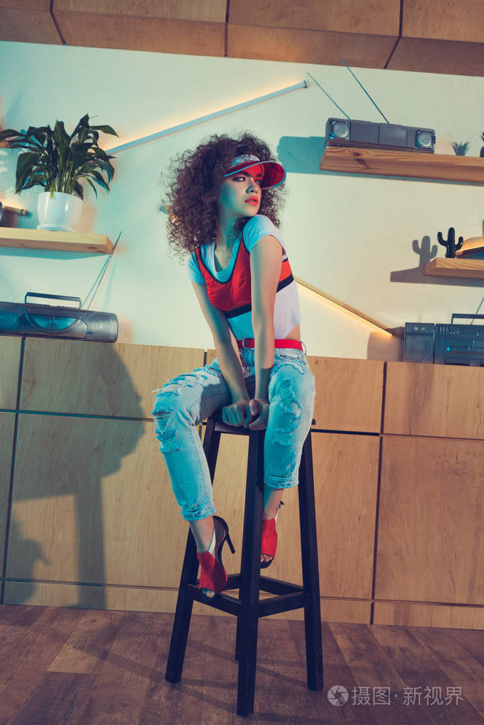 时尚的女人坐在酒吧的高脚凳上