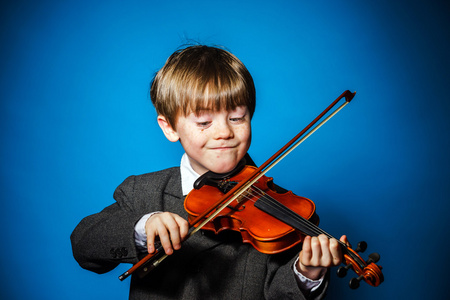 红发的学龄前儿童男孩用小提琴，音乐概念