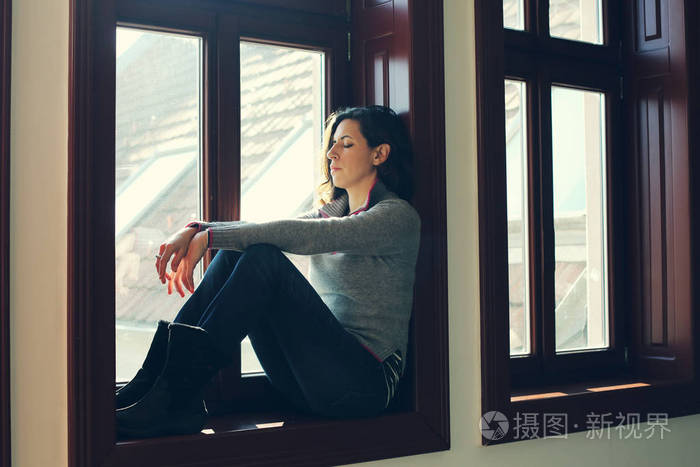 悲伤的女人望着不乏从窗外