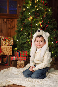 小男孩坐在附近一棵圣诞树