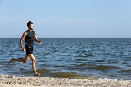 在海滩上慢跑的年轻男人