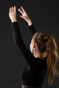芭蕾舞演员用双手在黑暗的背景上摆姿势