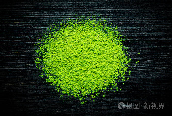 在黑色背景上的绿色抹茶粉