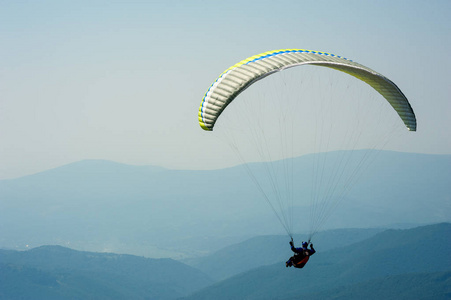 在阳光明媚的夏日，滑翔伞飞过山谷